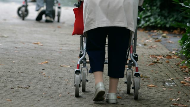 Frau schiebt Rollator über Plastersteine. Frau schiebt Rollator über Plastersteine.