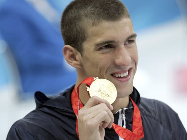 Michael Phelps präsentiert eine seiner Goldmedaillen.