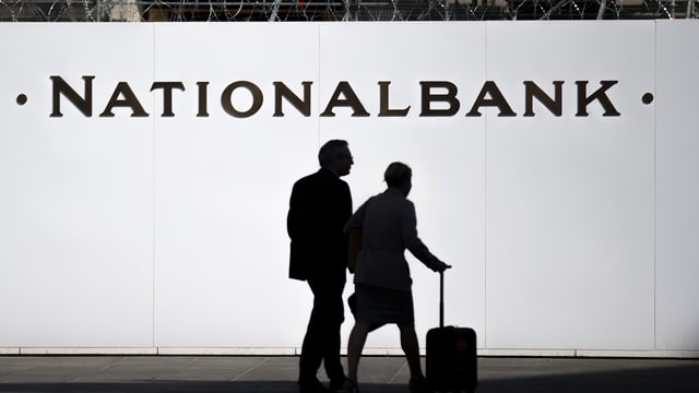 Zwei Personen vor einer Baustellenwand mit der Aufschrift Nationalbank auf dem Berner Bundesplatz Zwei Personen vor einer Baustellenwand mit der Aufschrift Nationalbank auf dem Berner Bundesplatz