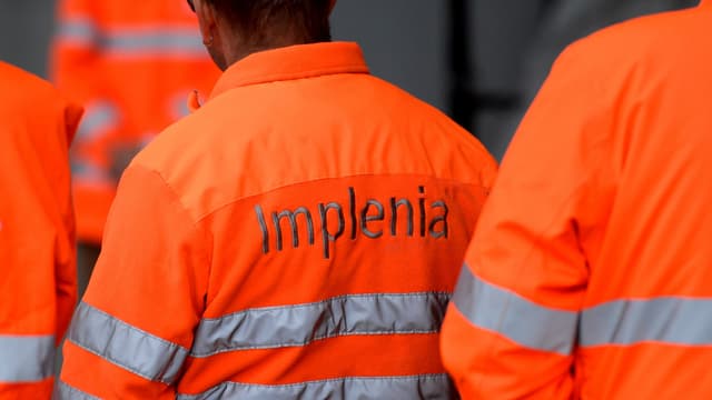 Mineure von Implenia in roter Arbeitskleidung mit dem Schriftzug "Implenia" auf dem Rücken Mineure von Implenia in roter Arbeitskleidung mit dem Schriftzug "Implenia" auf dem Rücken