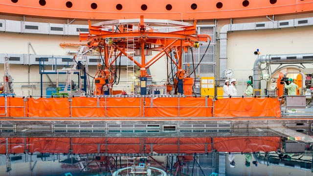 Reaktor, Orange Maschine, einige Leute drumherum. Reaktor, Orange Maschine, einige Leute drumherum.