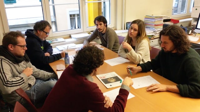 Fünf Männer und eine Frau sitzen diskutieren an einem Bürotisch. Fünf Männer und eine Frau sitzen diskutieren an einem Bürotisch.