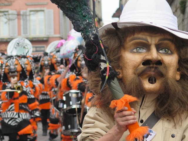 Tambourmajor mit Maske vor einer Guggenmusik