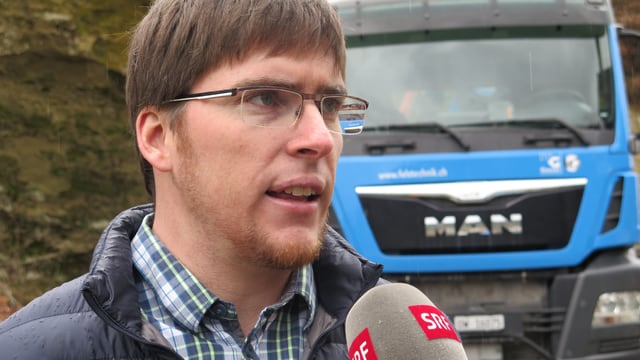 Mann spricht in SRF-Mikrofon vor grossem Lastwagen Mann spricht in SRF-Mikrofon vor grossem Lastwagen