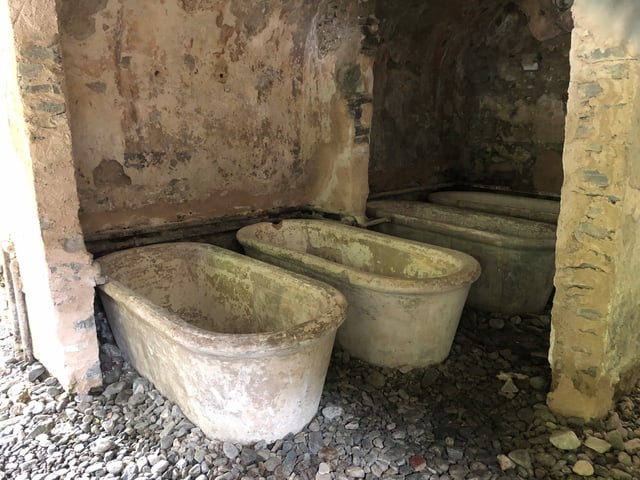 Alte Badewanne aus Stein im Keller einer Ruine.