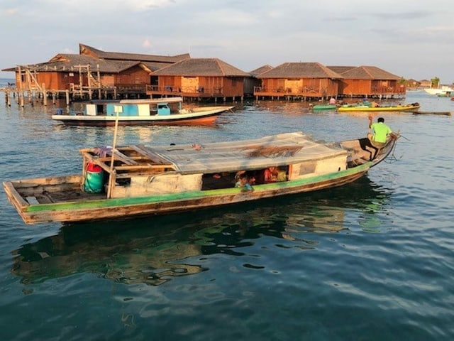 Ein Boot, im Hintergrund Wohnhäuser auf Pfählen im Wasser. Ein Boot, im Hintergrund Wohnhäuser auf Pfählen im Wasser.