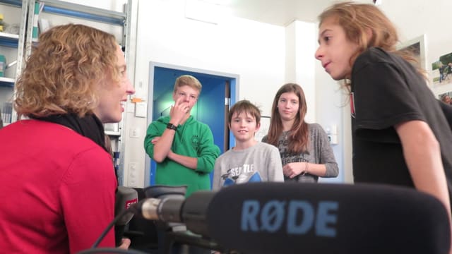 Reporterin erklärt Kindern eine Kamera. Reporterin erklärt Kindern eine Kamera.