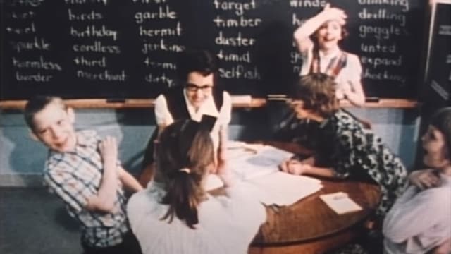 Kinder und Lehrerin sitzen um Tisch Kinder und Lehrerin sitzen um Tisch