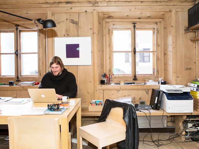 Ein Mann sitzt an einem Pult und tippt auf einem Laptop Ein Mann sitzt an einem Pult und tippt auf einem Laptop