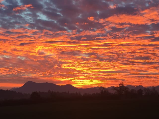 Farbiges Wolkenspiel über der Rigi. Die Farben wechseln von grau zu feuerrot.