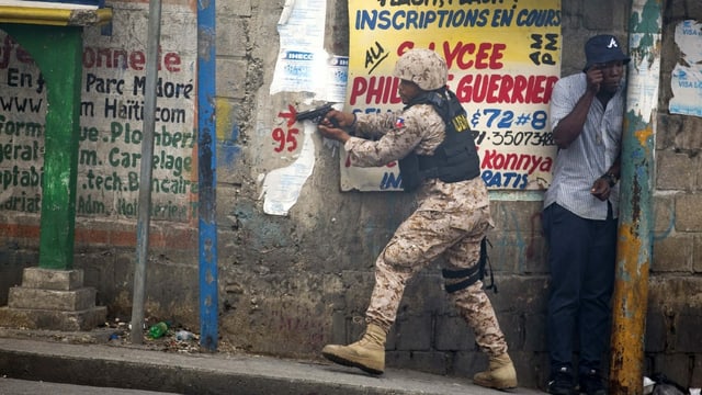 Ein haitianischer Polizist schiesst während einer Demonstration. Ein haitianischer Polizist schiesst während einer Demonstration.