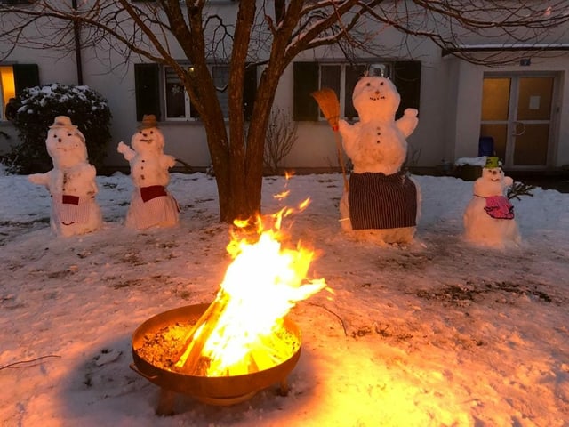Eine ganze Schneefamilie am Feuer