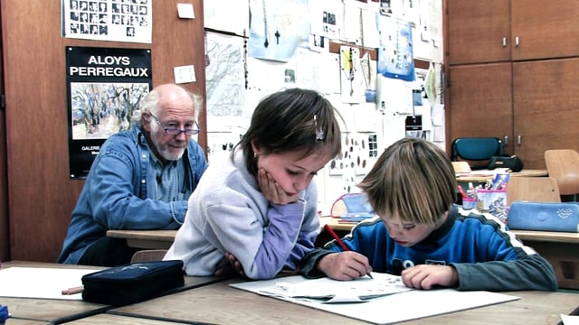 Lehrer Gilbert Hirschi im Hintergrund, zwei Schüler zeichnen im Vordergrund. Lehrer Gilbert Hirschi im Hintergrund, zwei Schüler zeichnen im Vordergrund.