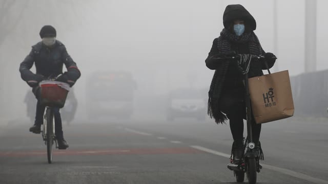 Velofahrer in Peking mit einer Schutzmaske. Velofahrer in Peking mit einer Schutzmaske.