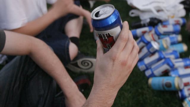 Jugendlicher mit Bierbüchse in der Hand, am Boden liegen weitere Büchsen Jugendlicher mit Bierbüchse in der Hand, am Boden liegen weitere Büchsen