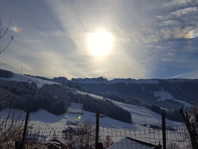 Die Sonnenscheibe schimmert durch dünne Wolken.