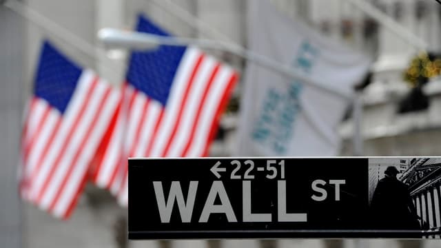 Wall Street-Strassenschild vor zwei amerikanischen Flaggen. Wall Street-Strassenschild vor zwei amerikanischen Flaggen.