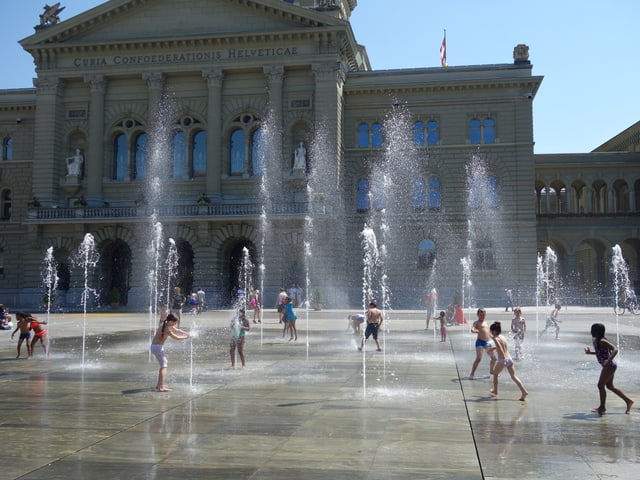 Kinder spielen unter den Wasserspiel beim Bundeshaus. Kinder spielen unter den Wasserspiel beim Bundeshaus.