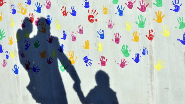 Ein Vater mit einem Kind auf dem Arm und einem an der Hand Ein Vater mit einem Kind auf dem Arm und einem an der Hand