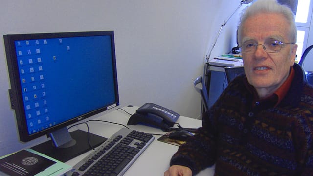 Der Basler Strafrechtsprofessor Peter Albrecht sitzend neben dem Computer in seinem Büro.