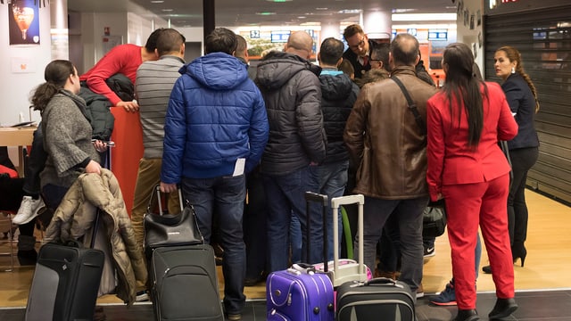 Menschen mit Koffern stehen vor einem Flugschalter. Menschen mit Koffern stehen vor einem Flugschalter.