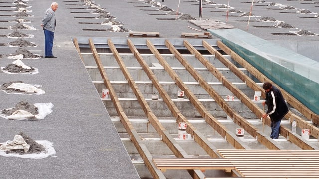 Mann auf einer Baustelle schaut einem Bauarbeiter zu. Mann auf einer Baustelle schaut einem Bauarbeiter zu.