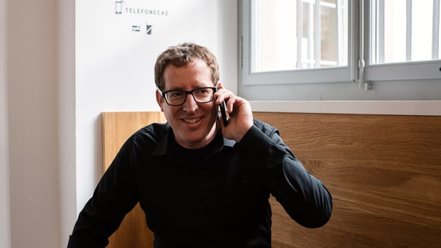 Ein Mann sitzt auf einer Bank und telefoniert mit seinem Smartphone. Ein Mann sitzt auf einer Bank und telefoniert mit seinem Smartphone.