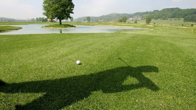 Ein Schatten eines Golfers, ein Golfball auf dem Rasen. Ein Schatten eines Golfers, ein Golfball auf dem Rasen.