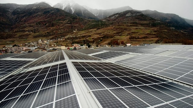 Solarzellen, im Hintergrund ein Dorf und Hügel. Solarzellen, im Hintergrund ein Dorf und Hügel.