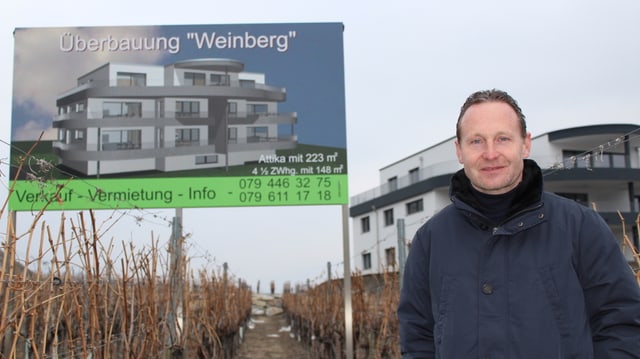 Ein Mann steht vor einem Bauplakat. Ein Mann steht vor einem Bauplakat.