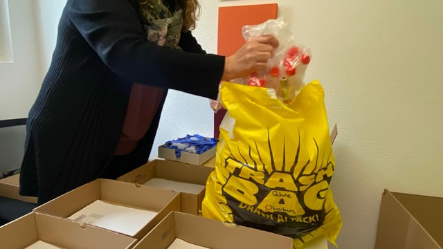Die Sekretärin packt die Säckli in einen gelben Sack. Die Sekretärin packt die Säckli in einen gelben Sack.