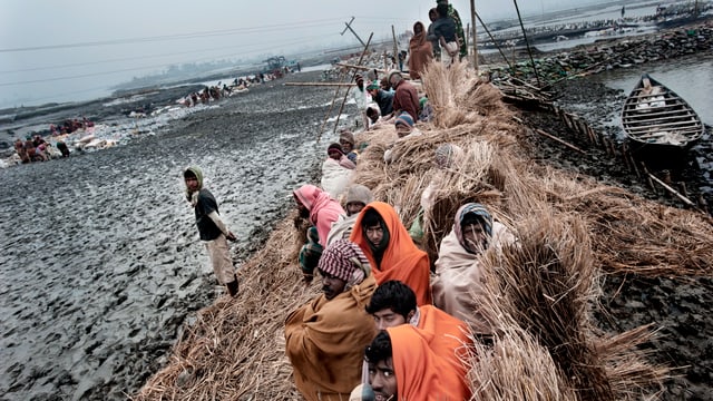 Leute in Bangladesch sitzen zusammengepfercht sind verhüllt auf einem Lehmhaufen. Leute in Bangladesch sitzen zusammengepfercht sind verhüllt auf einem Lehmhaufen.