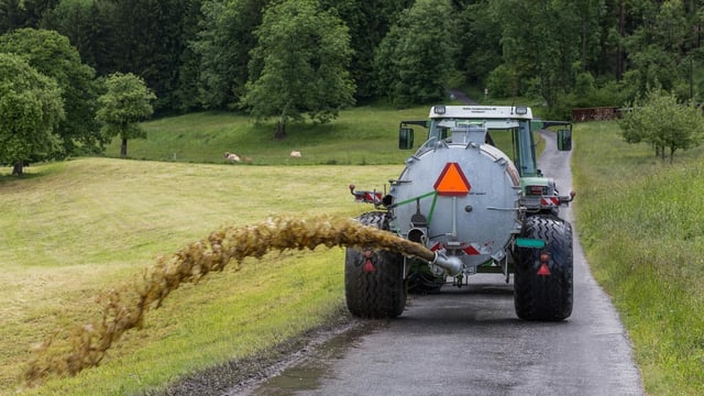Traktor zieht einen Tank, daraus wird Gülle verspritzt. Traktor zieht einen Tank, daraus wird Gülle verspritzt.