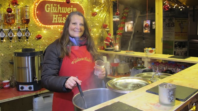 Eine Marktfahrerin schöpft Glühwein am Weihnachtsmarkt Eine Marktfahrerin schöpft Glühwein am Weihnachtsmarkt
