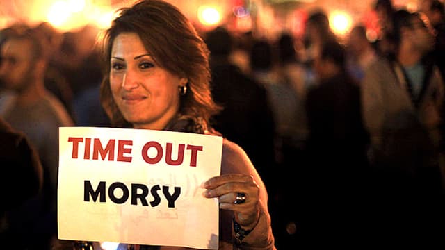Frau hält Schild in die Höhe. Darauf steht: Time out Morsy. Frau hält Schild in die Höhe. Darauf steht: Time out Morsy.