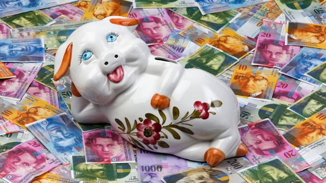 Ein Sparschwein liegt auf mehreren Geldnoten. Ein Sparschwein liegt auf mehreren Geldnoten.
