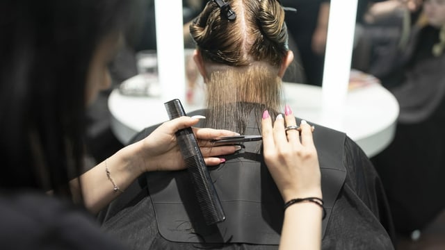 Eine Coiffeuse schneidet einer Kundin die Haare Eine Coiffeuse schneidet einer Kundin die Haare