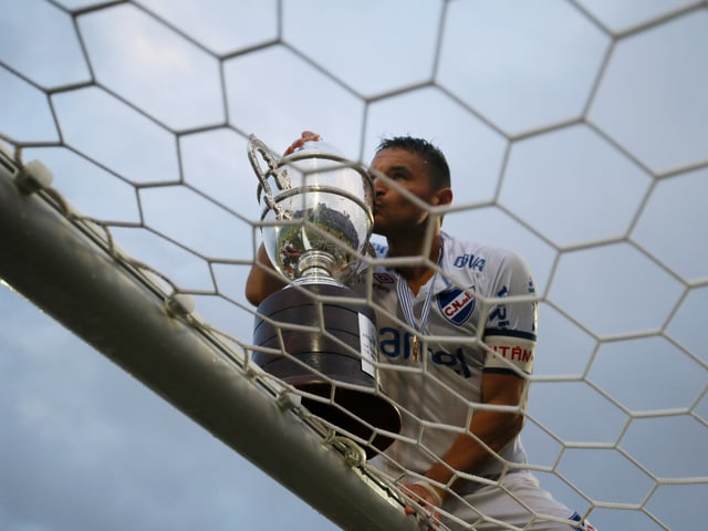 Nacionals Gonzalo Bergesio feiert mit der Trophäe auf dem Tor, nachdem sein Team die uruguayische Meisterschaft gewonnen hat.