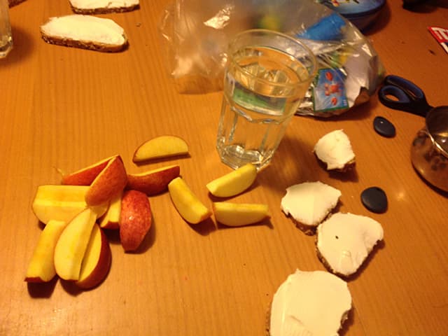 Apfelschnitze, ein Glas Wasser und Brötchen.