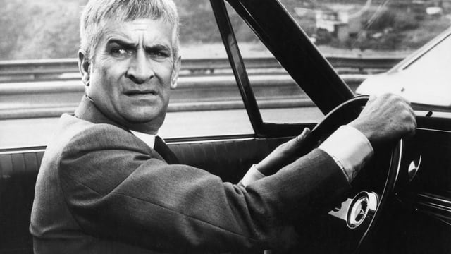 Louis de Funès hinter dem Lenkrad in einem Auto sitzend. (Schwarz-Weiss-Bild) Louis de Funès hinter dem Lenkrad in einem Auto sitzend. (Schwarz-Weiss-Bild)