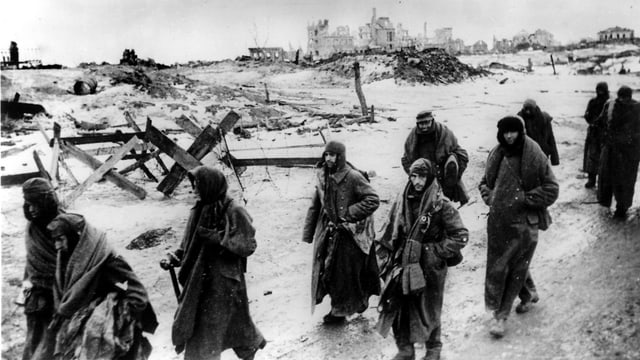 Gruppe von Soldaten in Mänteln läuft durch Trümmer. Gruppe von Soldaten in Mänteln läuft durch Trümmer.