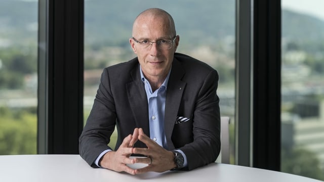 Mann sitzt an Tisch und schaut in Kamera. Mann sitzt an Tisch und schaut in Kamera.