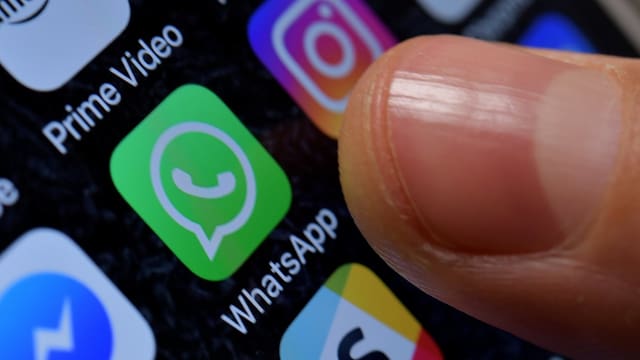 Ein Finger weist auf das WhatsApp-Symbol auf einem Bildschirm. Ein Finger weist auf das WhatsApp-Symbol auf einem Bildschirm.