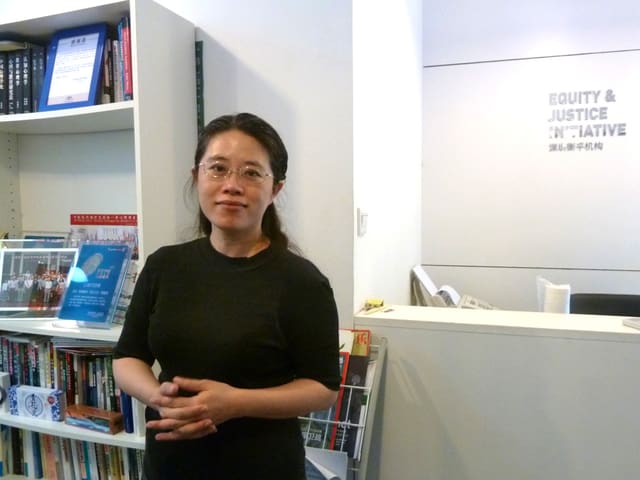 Eine junge Frau steht in einem weissen Büro, im Hintergrund steht ein Bücherregal. Eine junge Frau steht in einem weissen Büro, im Hintergrund steht ein Bücherregal.