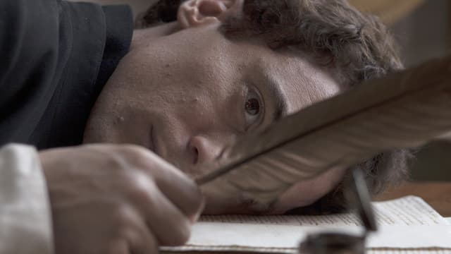Ein Schriftsteller mit dem Kopf auf seinen Schriften betrachtet die Feder in seiner Hand. Ein Schriftsteller mit dem Kopf auf seinen Schriften betrachtet die Feder in seiner Hand.