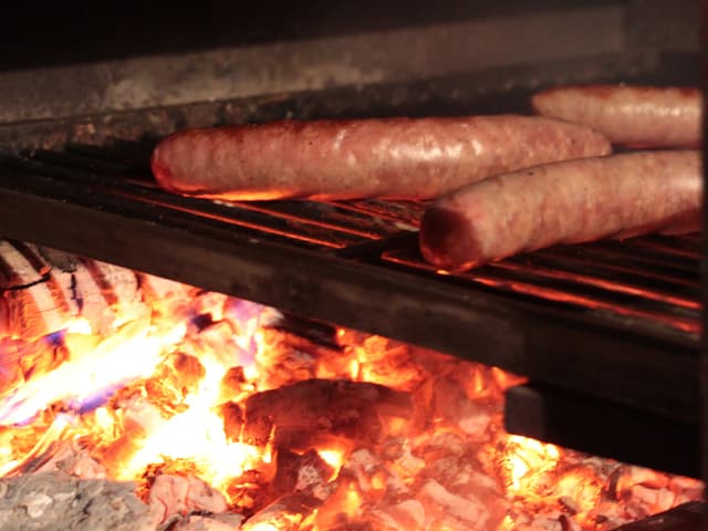 Würste brutzeln über einem Feuer.