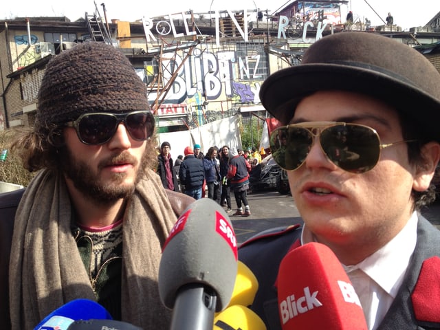 Zwei maskierte Besetzer geben Interviews. Zwei maskierte Besetzer geben Interviews.