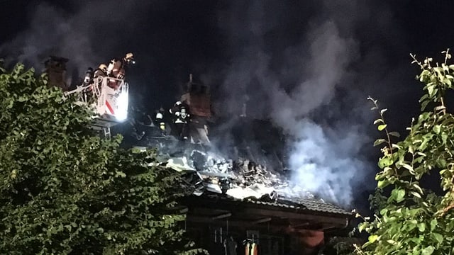 Ein Feuerwehrmann in einer Drehleiter über dem Haus Ein Feuerwehrmann in einer Drehleiter über dem Haus