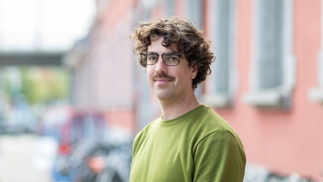 ein junger Mann mit Brille und grünem Pullover ein junger Mann mit Brille und grünem Pullover