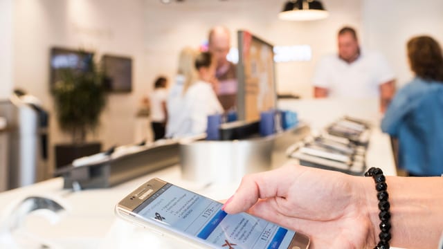 Eine Frau schaut sich ein Handy an in einem Laden. Eine Frau schaut sich ein Handy an in einem Laden.